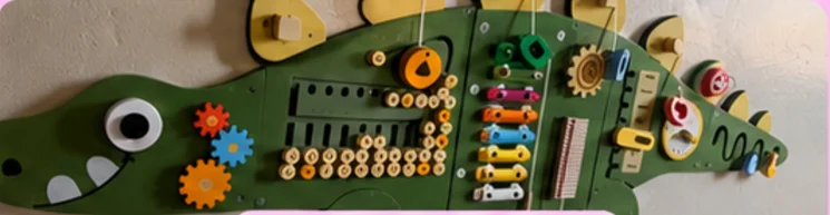 A crocodile-shaped sensory wall with gears, latches and a xylophone